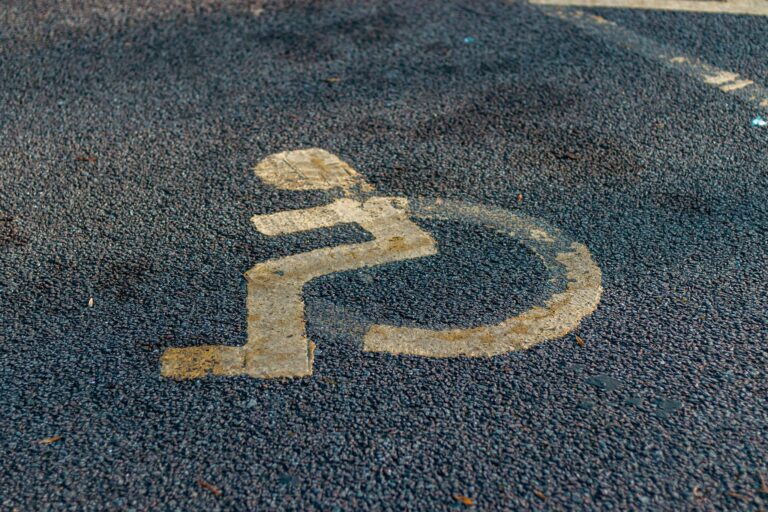 Close-up of a weathered handicap sign painted on a pavement, emphasizing accessibility.